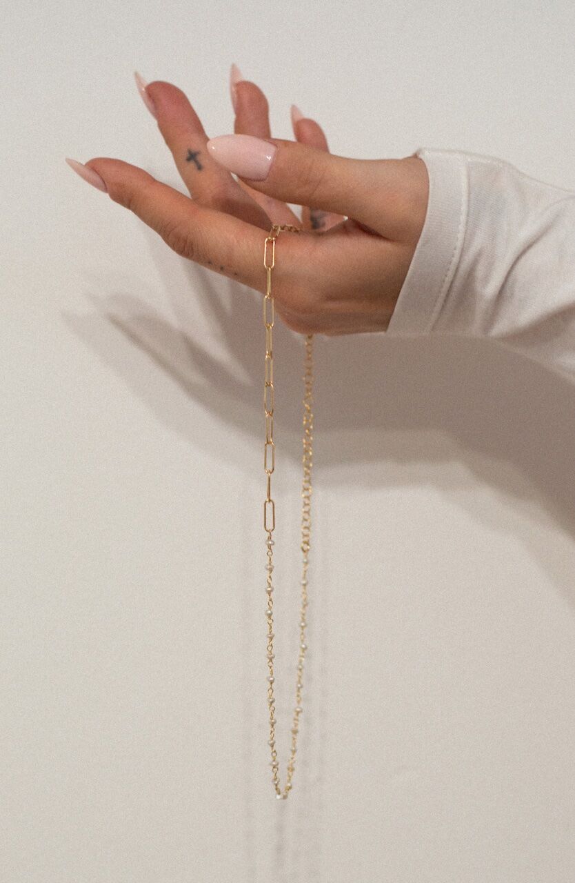 Layered gold chains held in hand