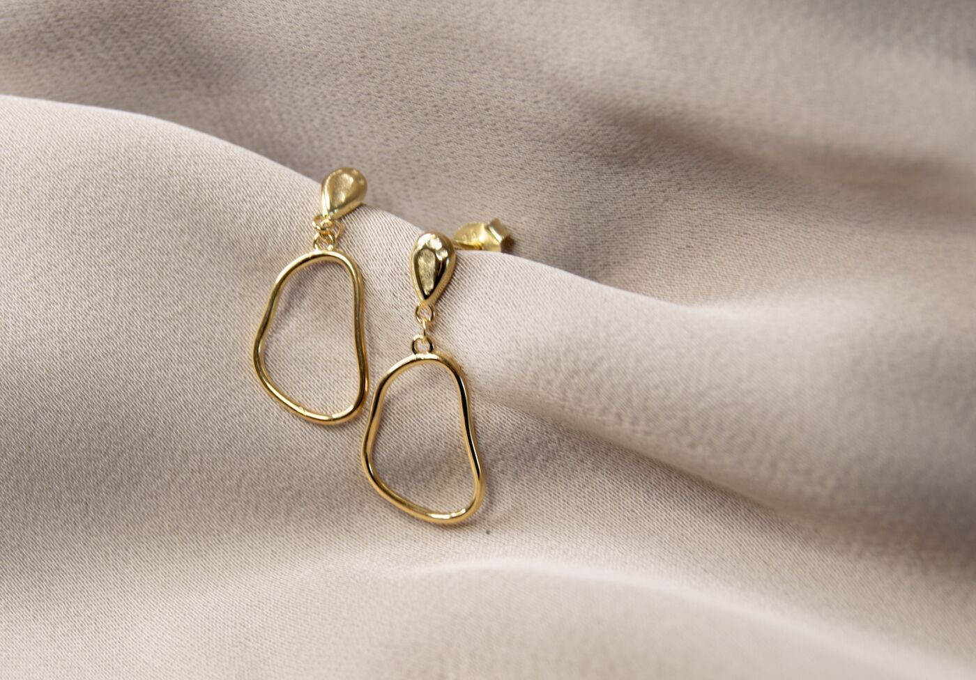 Gold drop earrings on draped silk