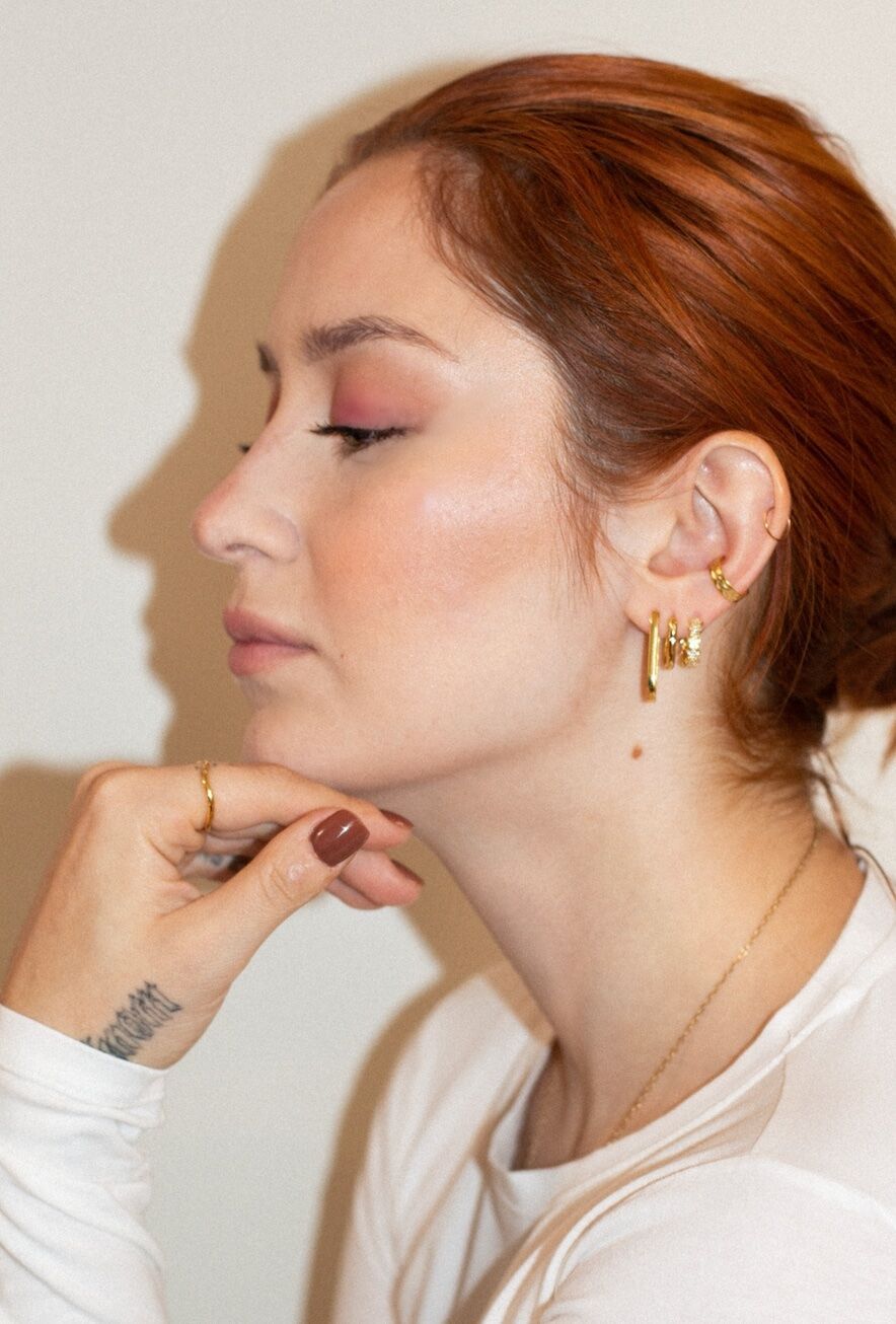 Model wearing layered gold ear stack — profile view