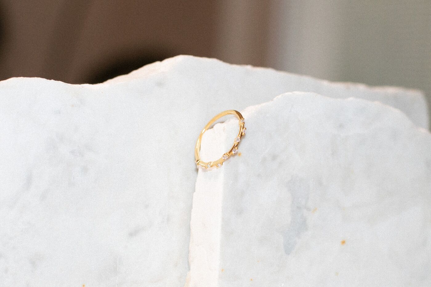 Delicate stone-set gold ring on white marble
