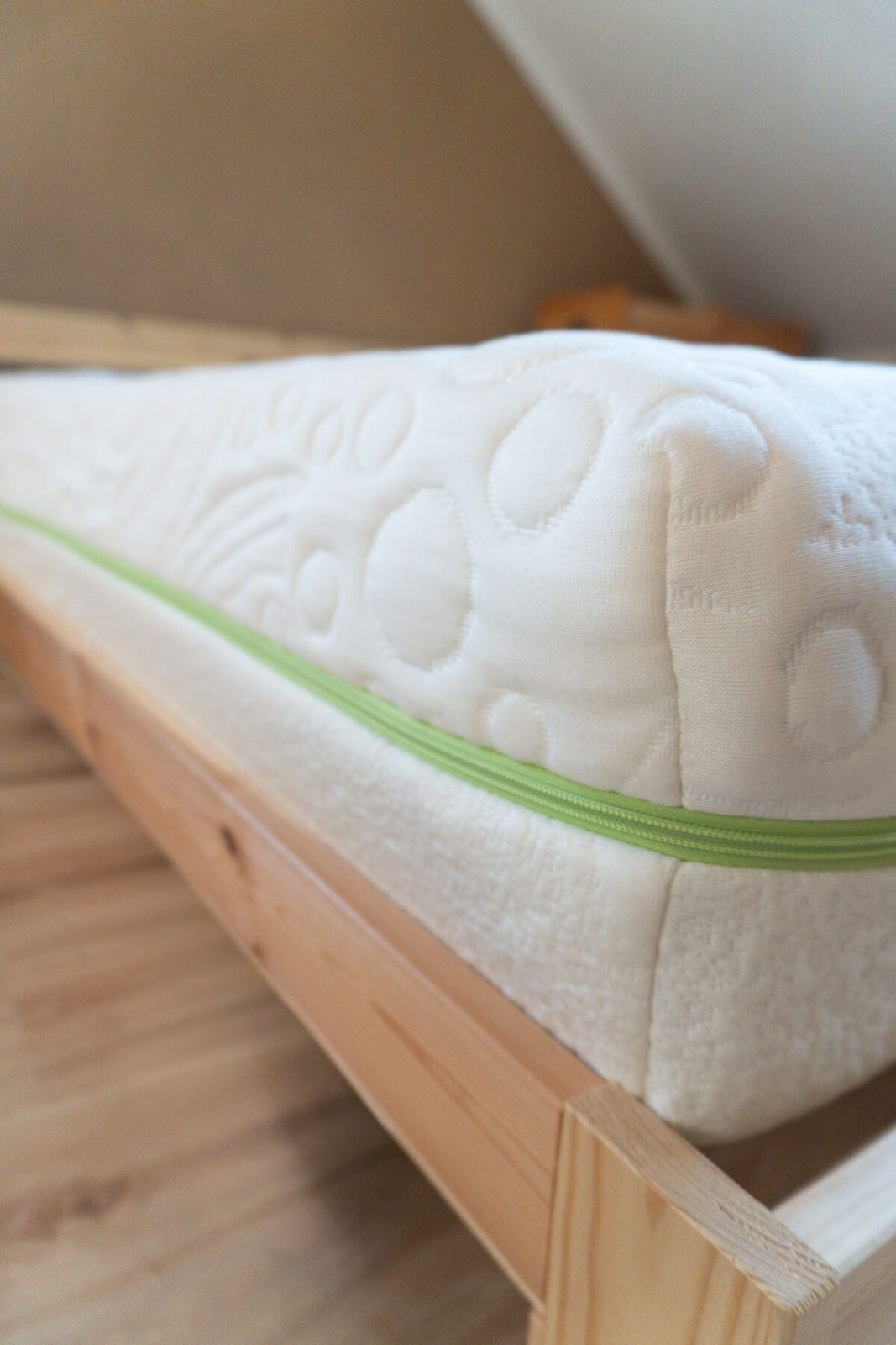 Bedton mattress on wooden bed frame — green zipper detail
